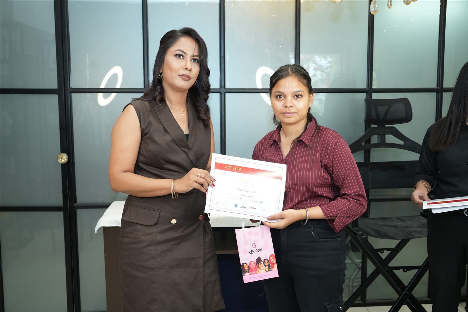 A student receiving her certificate from Anthéa at the Academy