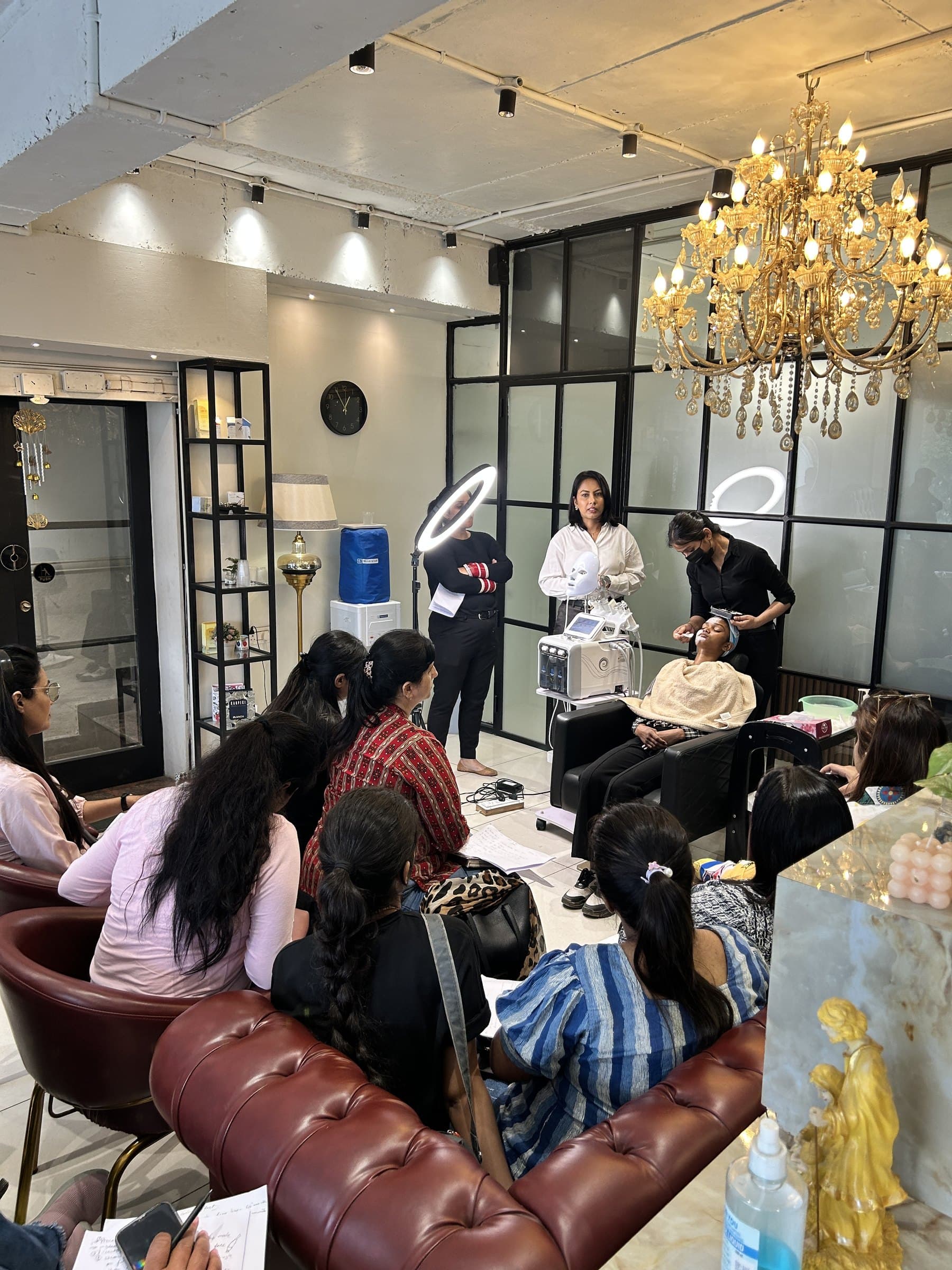 Anthéa demonstrating a facial treatment to a class of students on the academy floor