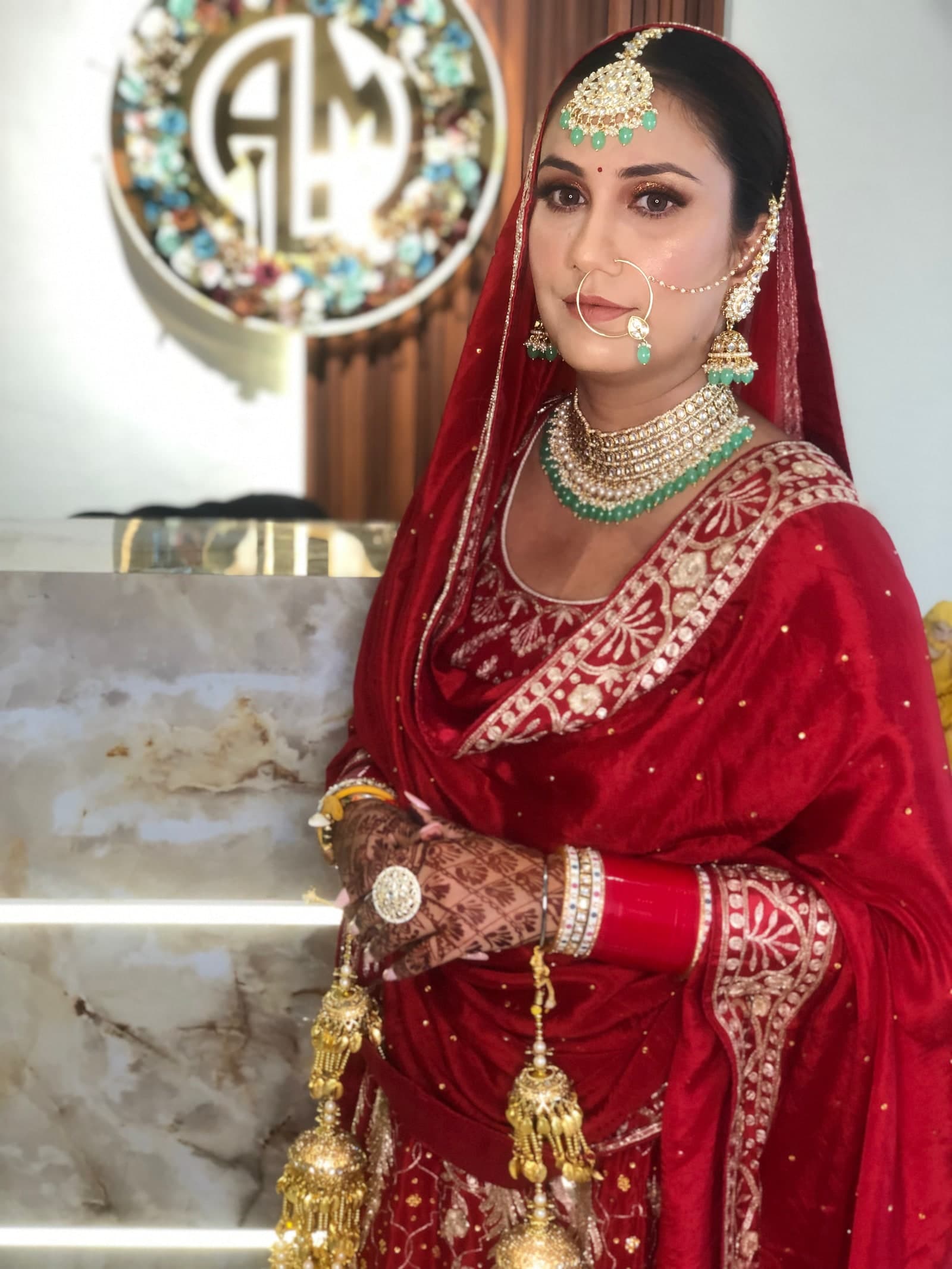 A bride in a red velvet saree with kundan and emeralds