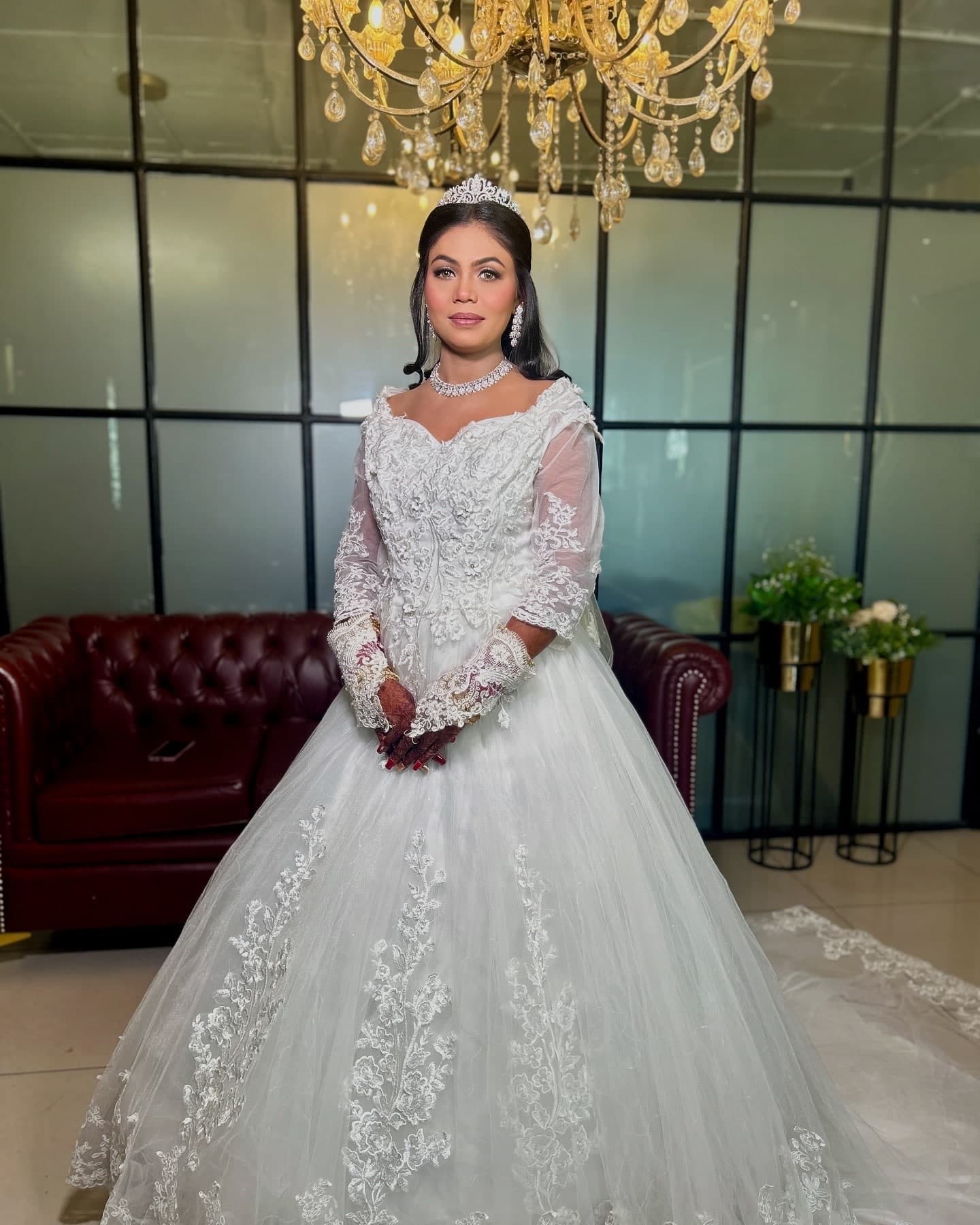 A bride in a white lace gown wearing a tiara