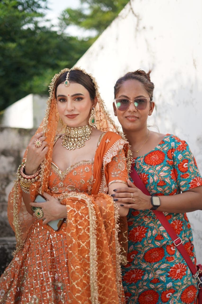 Anthéa with a client styled in a gold-worked orange lehenga on location