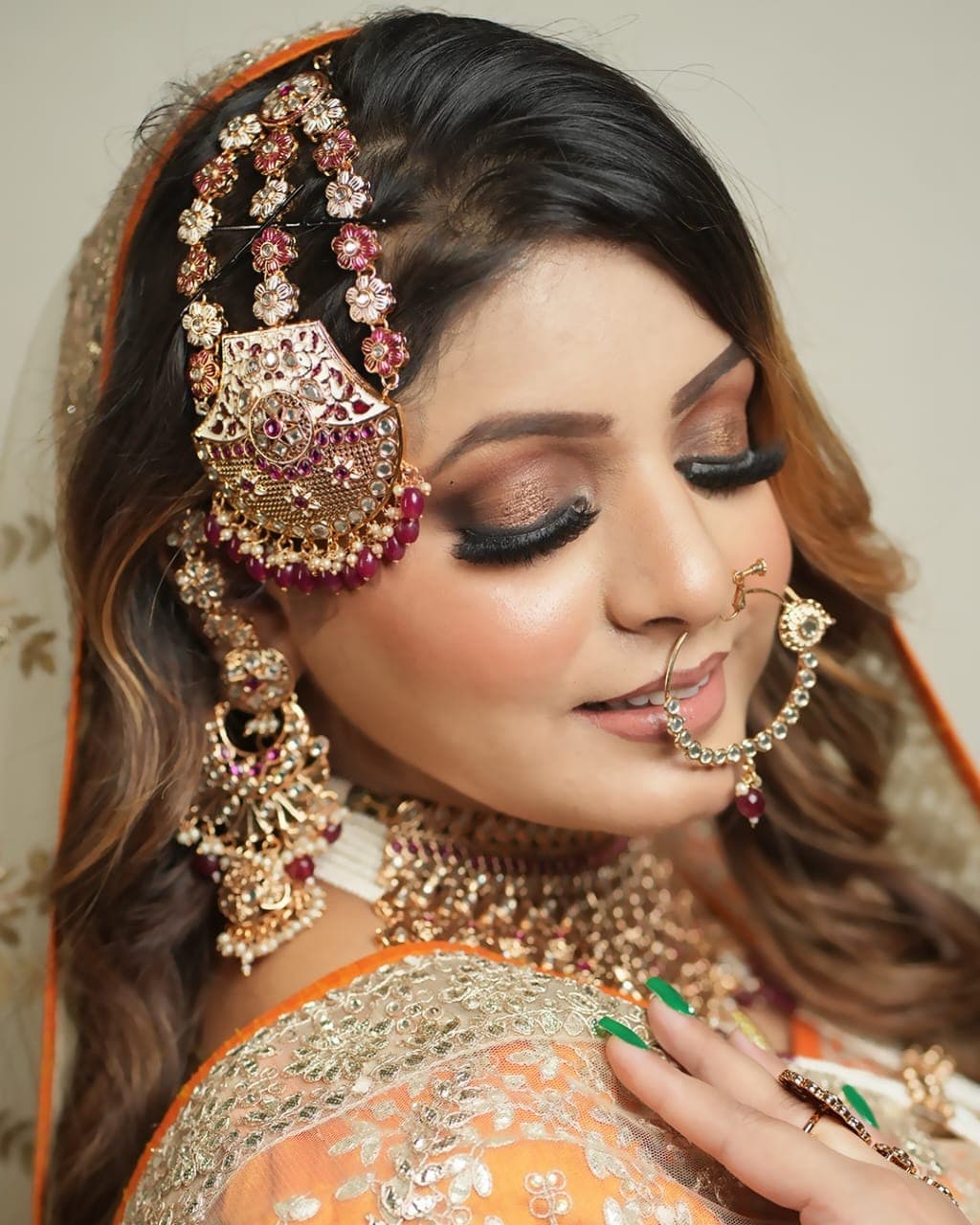 An occasion look in orange with a pink and gold matha patti