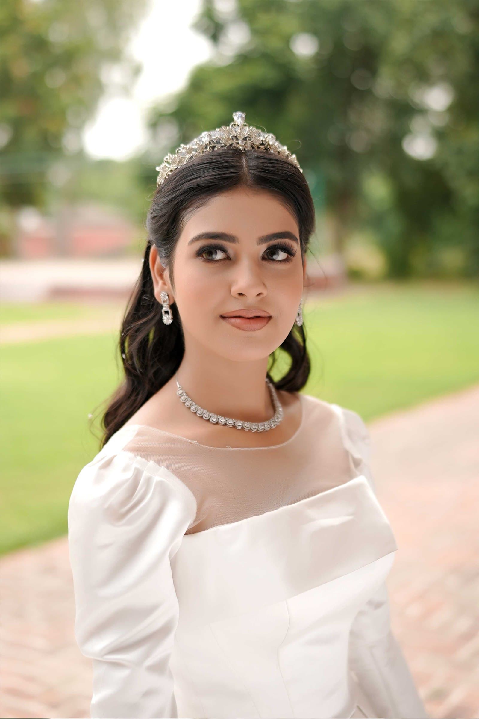 A bride in a white gown and tiara photographed on the lawn