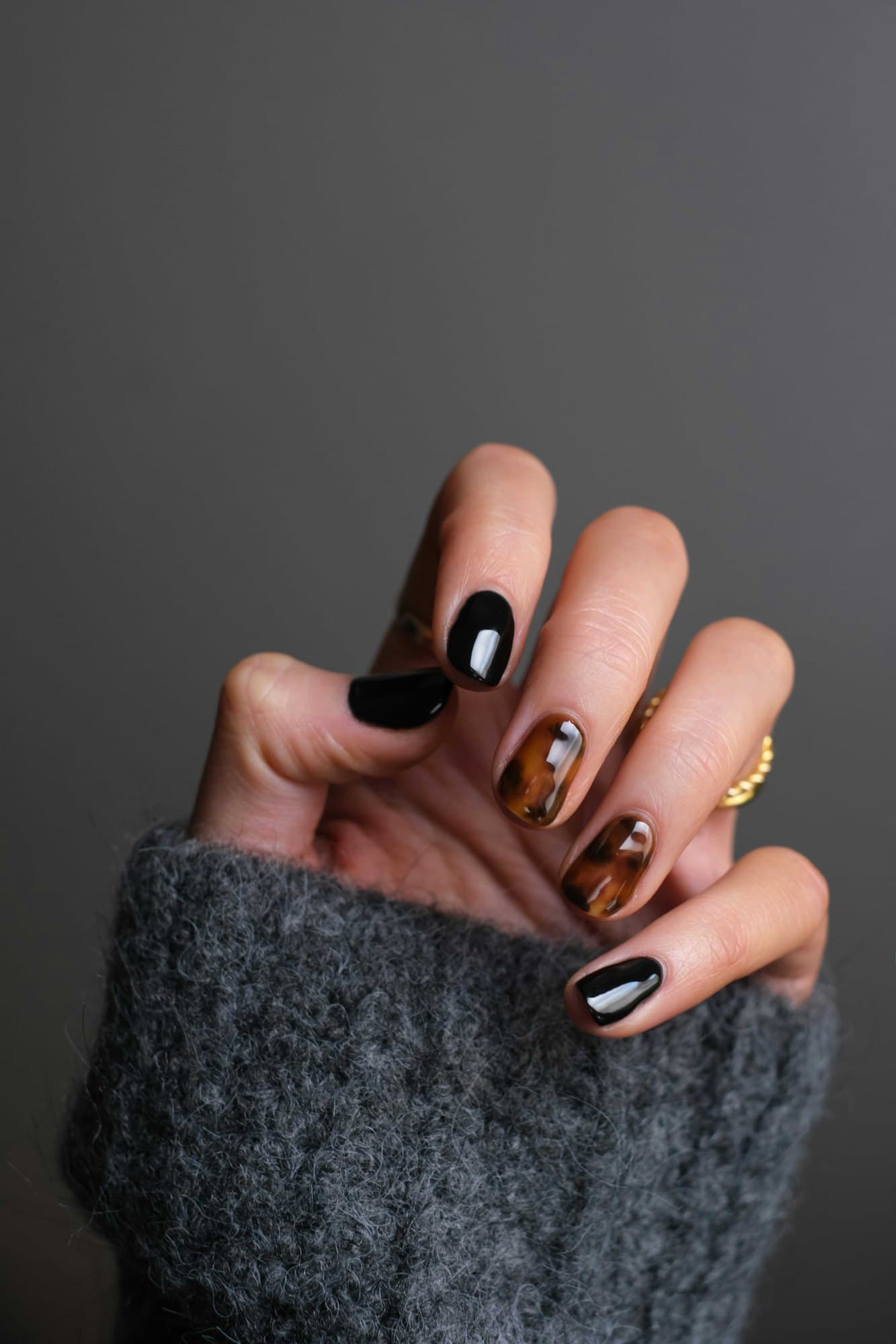 A hand showing a set of dark, glossy painted nails