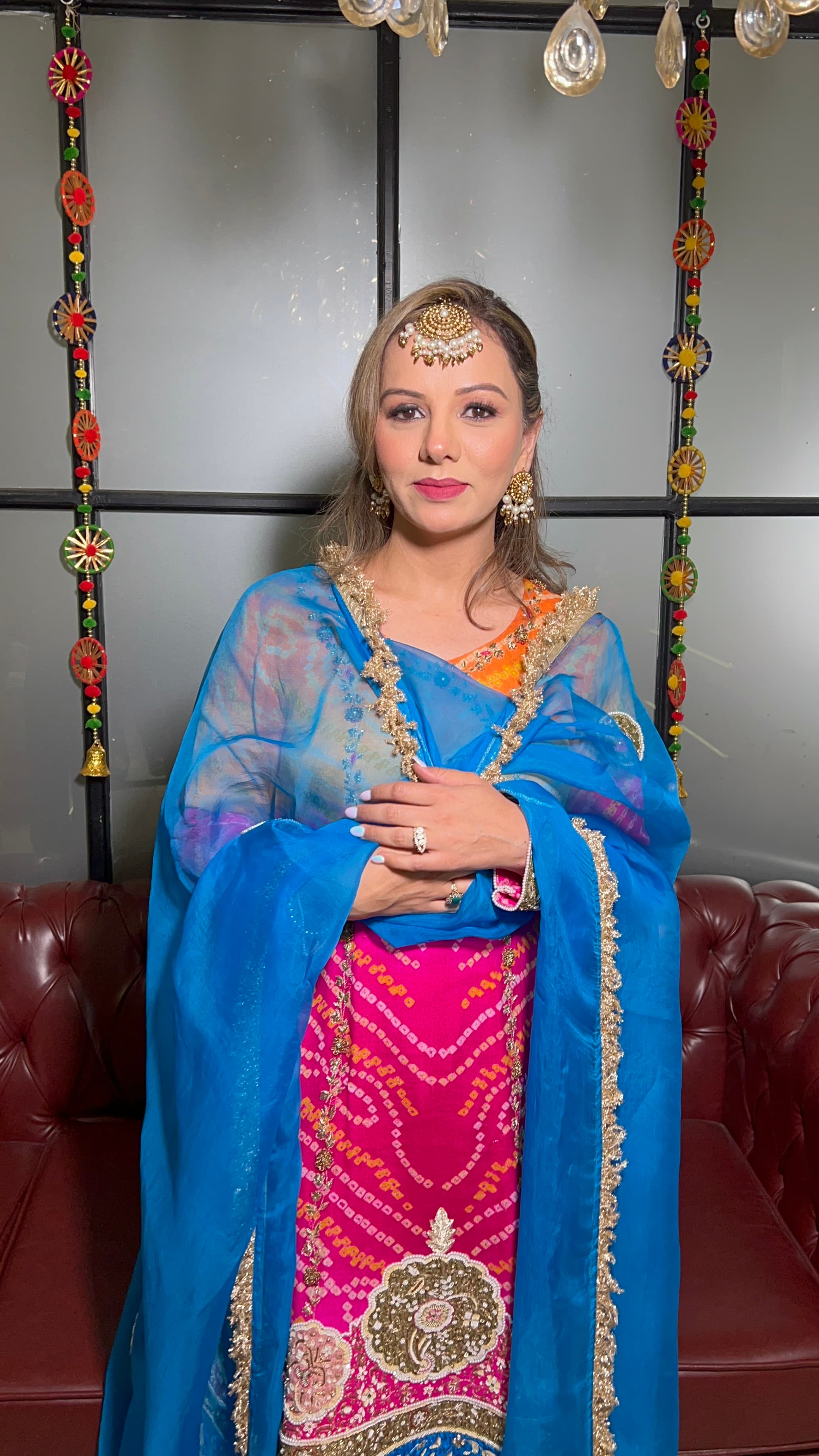 A client in a bandhani suit under a blue organza dupatta