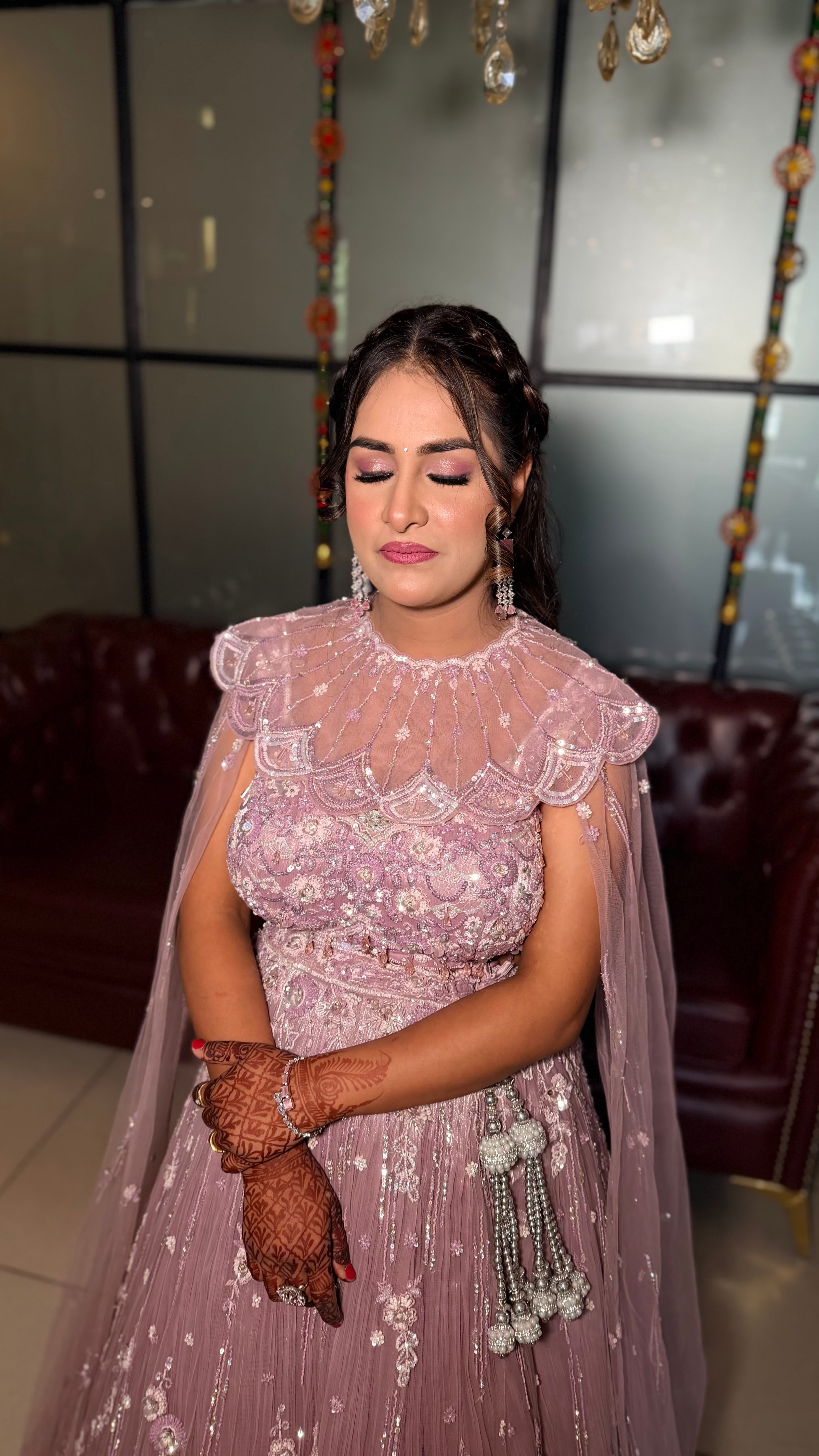 A bride in a mauve cape gown with mehndi on her hands
