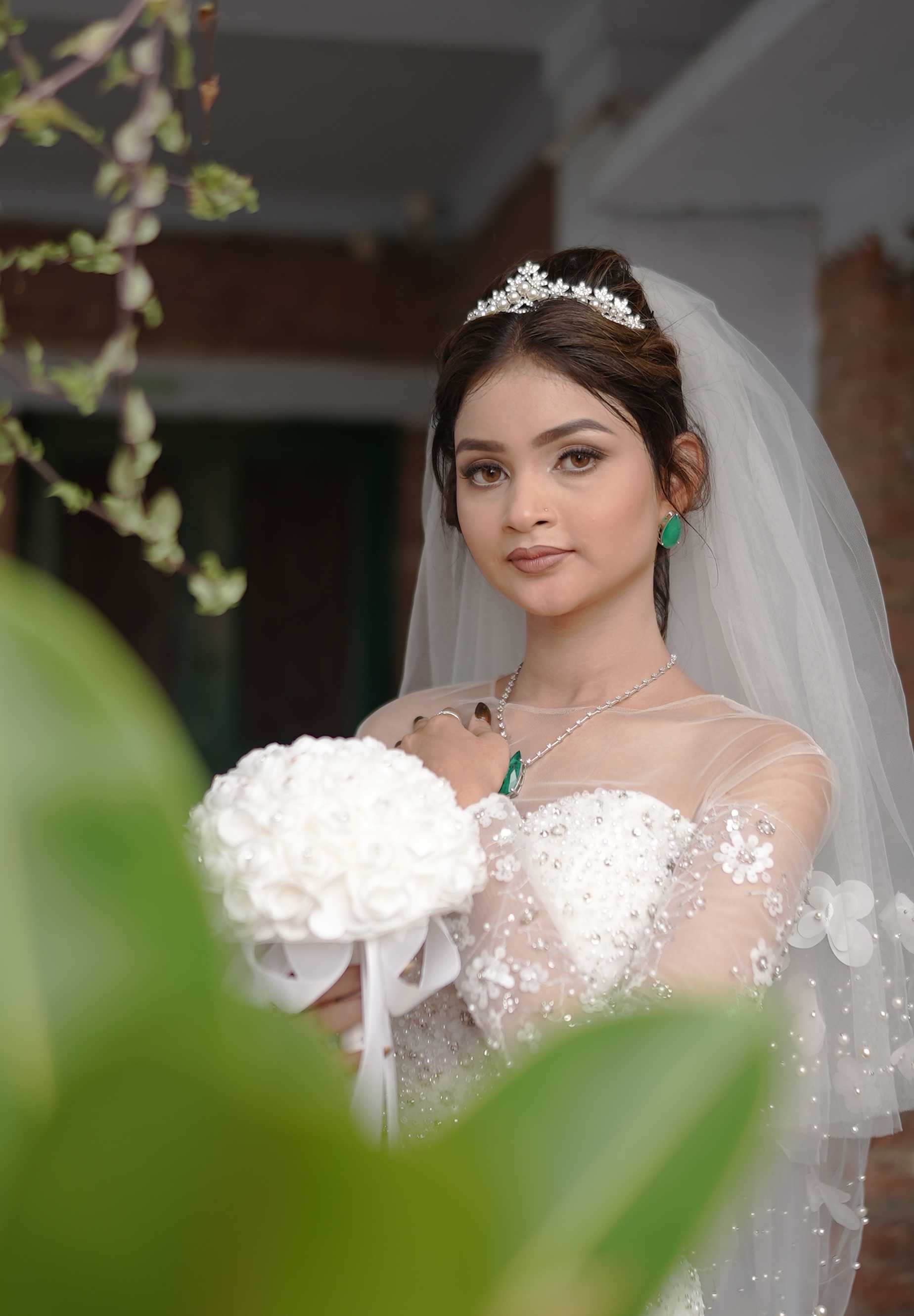 A bride in a white gown and tiara holding a white rose bouquet