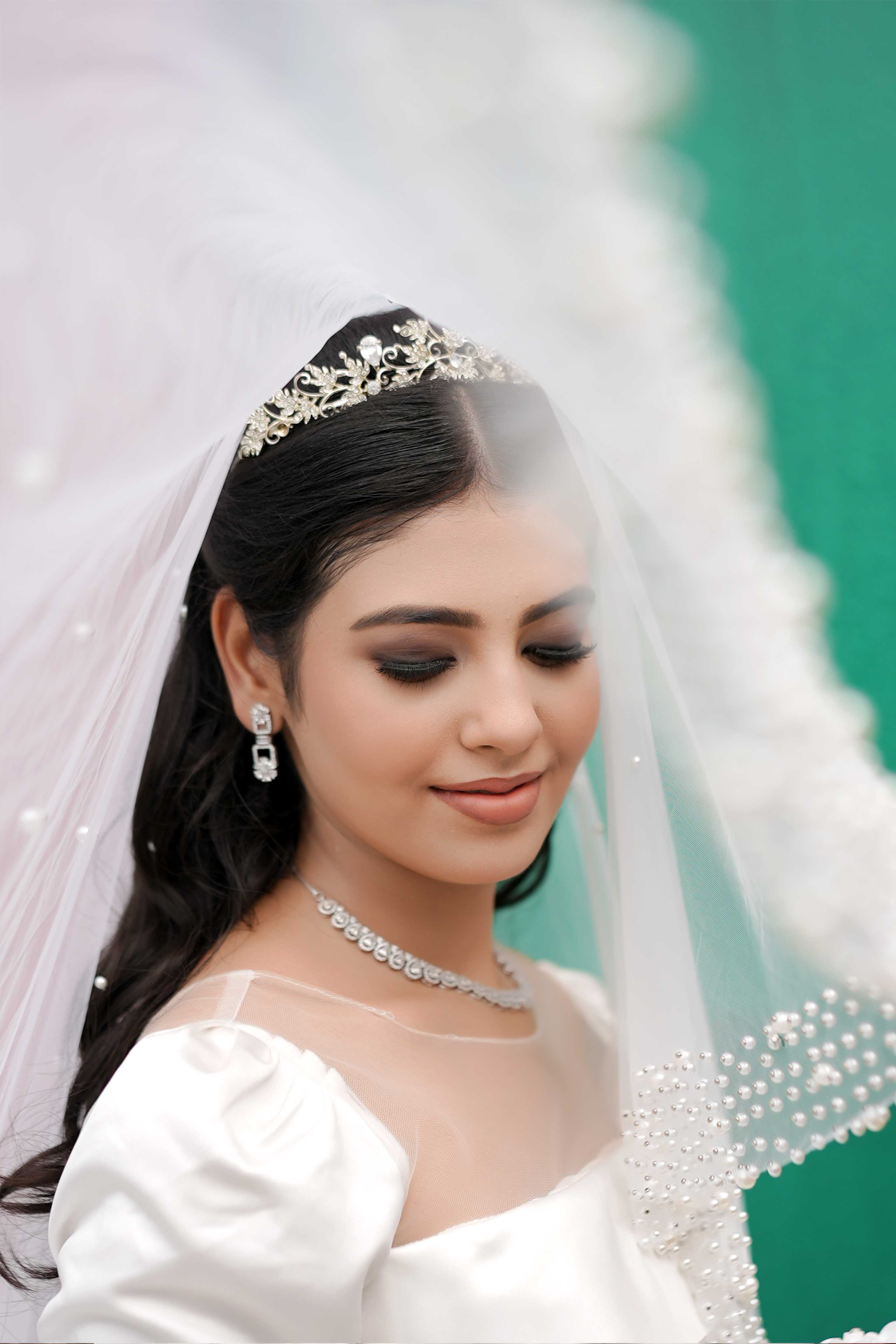 A bride beneath a pearl-trimmed veil with a crystal tiara