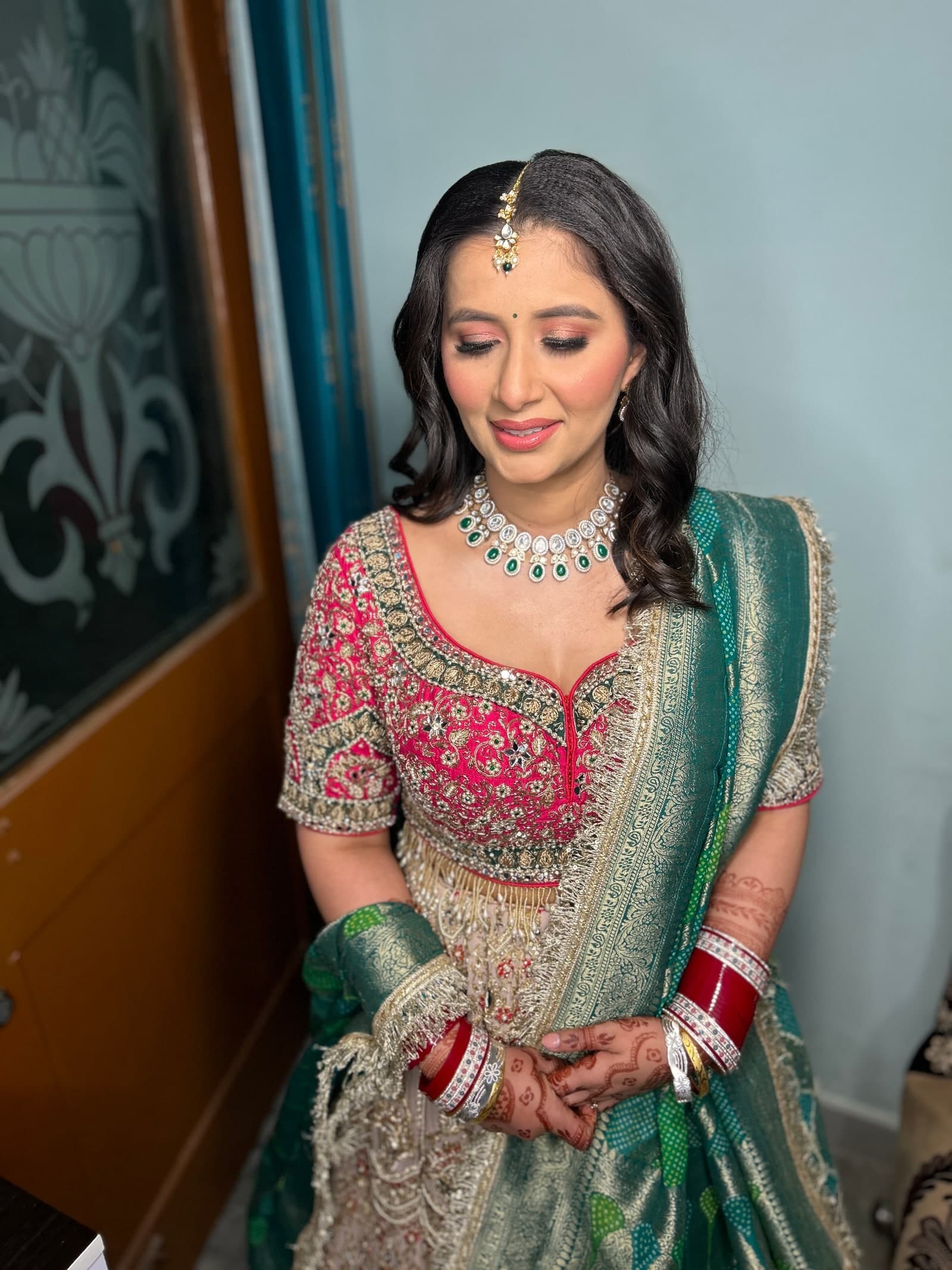 A bride in a pink and green lehenga with soft waves