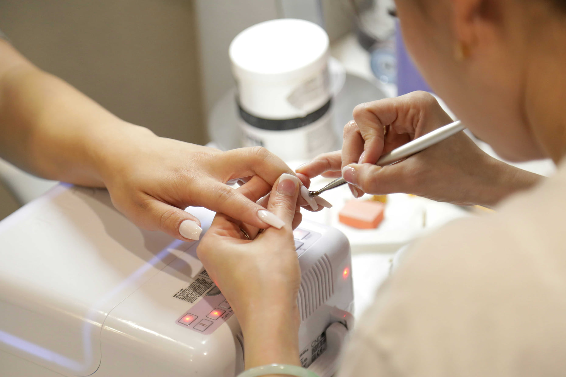 A gel nail application in progress under the lamp at Anthéa Makeover in Jalandhar