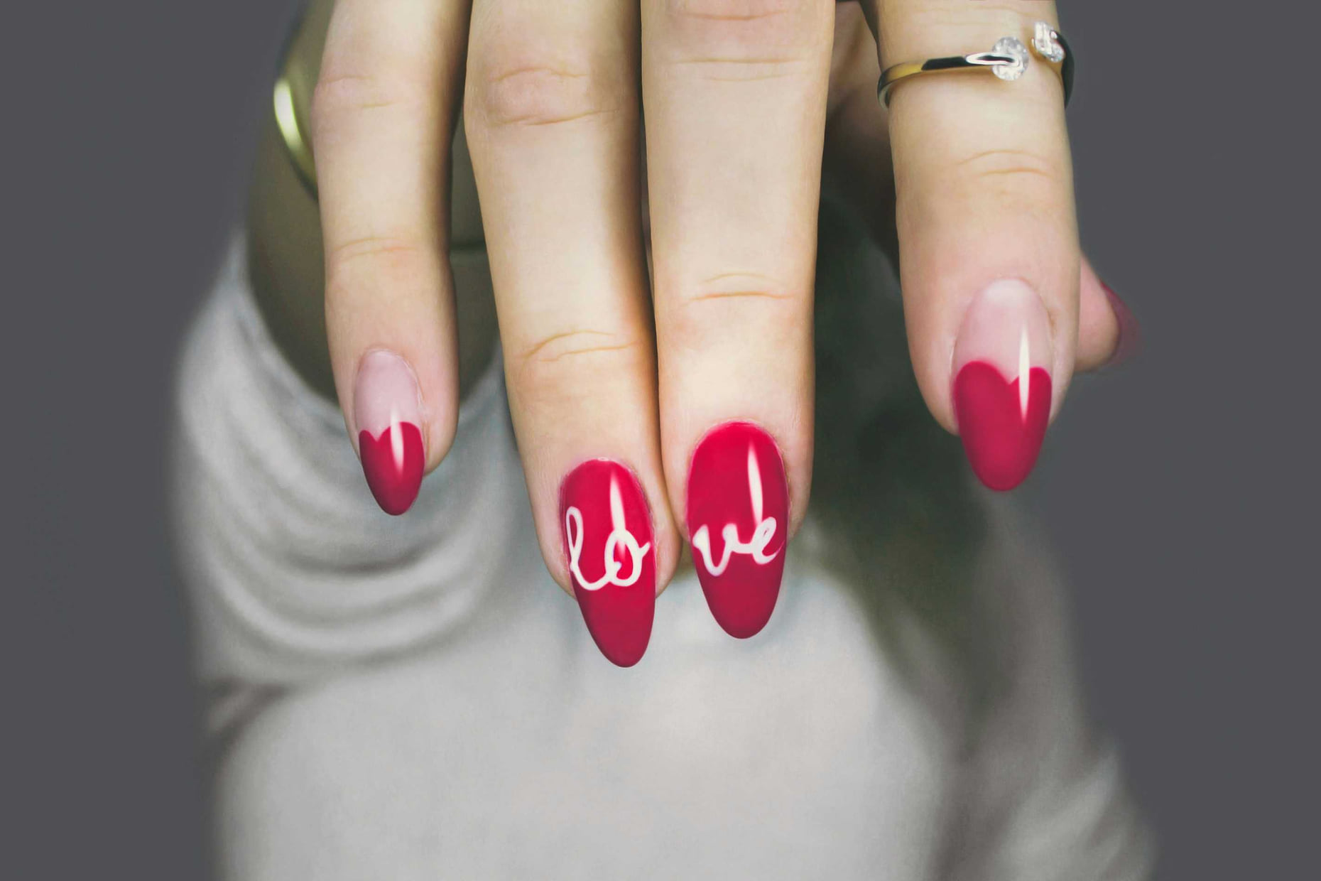 Red nail art with heart-shaped French tips and hand-painted lettering at Anthéa Makeover in Jalandhar